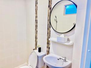 a bathroom with a toilet and a sink and a mirror at The Sunset Bangsaen in Ban Rong Khoei