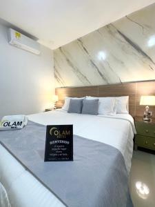 a hotel room with a large bed with a sign on it at Hotel Olam Deluxe Valledupar in Valledupar