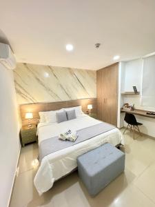 a bedroom with a large white bed and a desk at Hotel Olam Deluxe Valledupar in Valledupar