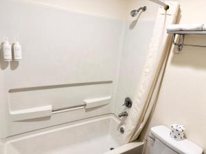 a bathroom with a white tub and a toilet at Super 8 by Wyndham Selma/Fresno Area in Selma +17 photos
