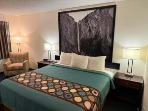 a hotel room with a bed and a chair at Super 8 by Wyndham Selma/Fresno Area in Selma