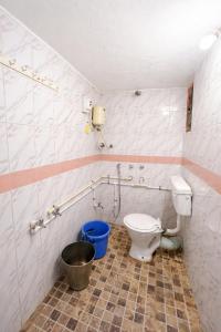 a bathroom with a toilet and a bucket in it at Peaceful Family Bungalow Near Mahalakshmi Temple in Kolhapur +9 photos