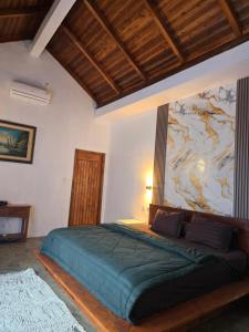 a bedroom with a large bed with a painting on the wall at Villa Lamorna in Krui