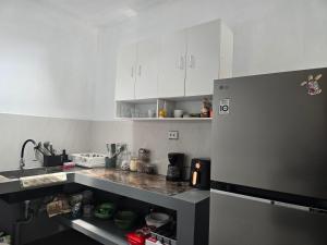 a kitchen with white cabinets and a gray refrigerator at Villa Lamorna in Krui