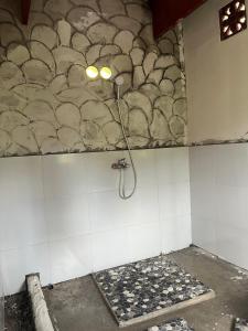 a bathroom with a shower and a tile wall at Live lombok homestay in Batukliang