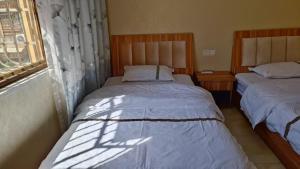 two twin beds in a room with a window at 春栖客栈 in Chuanxingpu