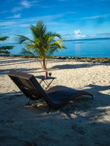 a chair and table on a beach with a palm tree at HilNer's Beach Resort in Alegria