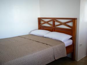 a bed with a wooden frame and white pillows at HilNer's Beach Resort in Alegria