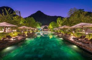 a pool with chairs and umbrellas at night at Aravinda Resort Ninh Binh in Ninh Binh