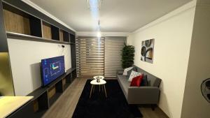 a living room with a couch and a tv at Condo luminity exclusivo 2D-2B incluye piscina parking y wifi gratis check in y seguridad 24 hrs in Los Ángeles