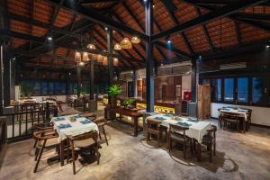 a restaurant with tables and chairs and windows at Aravinda Resort Ninh Binh in Ninh Binh