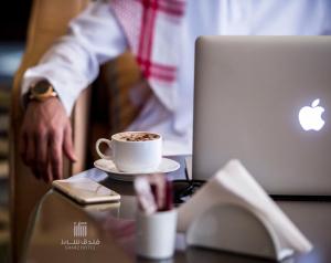 a man sitting at a table with a cup of coffee at Sharz Hotel in Buraydah