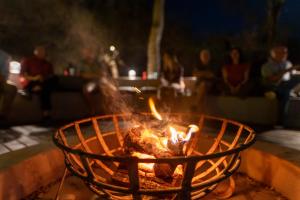 a fire in a basket with people in the background at Rukiya Safari Camp in Hoedspruit +169 photos