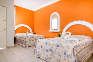 two beds in a room with orange walls at Hotel del Tajo in Salamanca