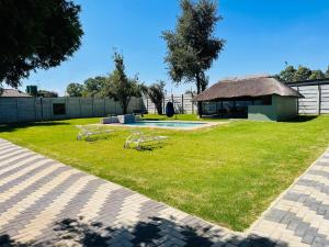 a yard with two picnic tables and a building at Vilanculos Guesthouse in Brakpan