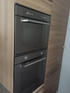 a black oven in a kitchen with wooden cabinets at Gastenverblijf Eindhoven in Eindhoven