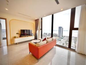 a living room with an orange couch and large windows at Căn hộ tại các tòa ICON40 - ALACARTE - NEW LIFE TOWER in Ha Long