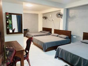 a bedroom with two beds and a table and a desk at Sensitha Holiday home in Anuradhapura +16 photos