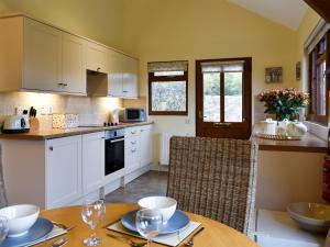 a kitchen with white cabinets and a table with chairs at Lavender Lea in Landford