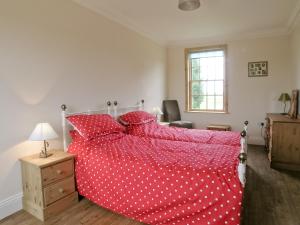 a bedroom with a red bed with white polka dots at Rascal Wood in Holme upon Spalding Moor +9 photos