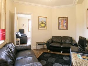 a living room with a leather couch and a television at Rascal Wood in Holme upon Spalding Moor