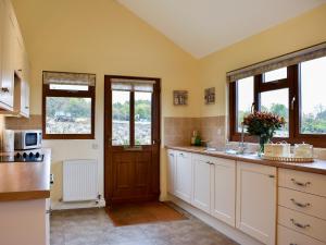 a kitchen with white cabinets and a sink and windows at Lavender Lea in Landford