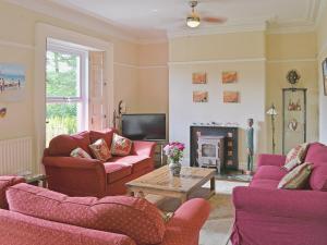 a living room with purple furniture and a fireplace at Holly Lodge in Gilcrux