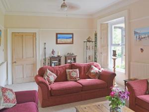 a living room with a red couch and a window at Holly Lodge in Gilcrux
