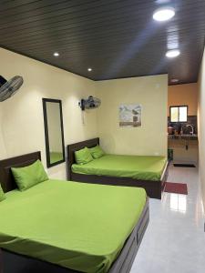 two beds in a room with green sheets at Sensitha Holiday home in Anuradhapura