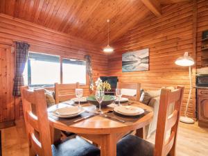 a wooden dining room with a table and chairs at Lochside Log Cabin in Brora