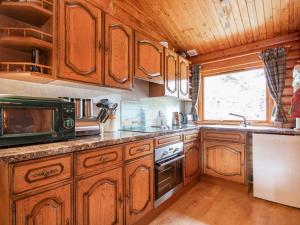 a large kitchen with wooden cabinets and a window at Lochside Log Cabin in Brora