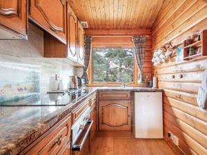 a kitchen with wooden cabinets and a white refrigerator at Lochside Log Cabin in Brora