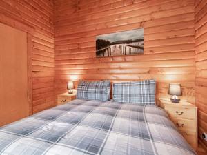 a bedroom with a bed in a wooden wall at Lochside Log Cabin in Brora