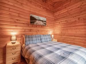 a bedroom with wooden walls and a bed and a night stand at Lochside Log Cabin in Brora +8 photos