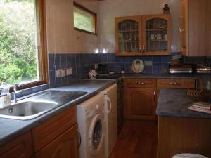 a kitchen with a sink and a washing machine at Achnacarry Cottage in Evelix