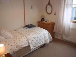 a bedroom with a bed and a dresser and a window at Achnacarry Cottage in Evelix