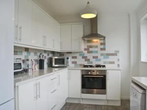 a kitchen with white cabinets and a stove top oven at La Falda in Sutton on Sea