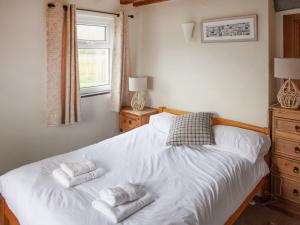 a bedroom with a white bed with two towels on it at Bakery - Ukc4675 in Clynnog-fawr