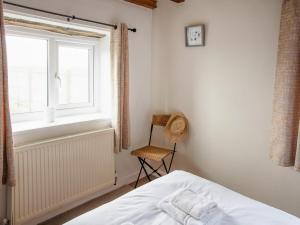 a bedroom with a bed and a chair and a window at Bakery - Ukc4675 in Clynnog-fawr +2 photos