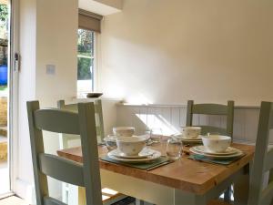 a dining room table with chairs and a wooden table with glasses at Wells Cottage in Hook Norton