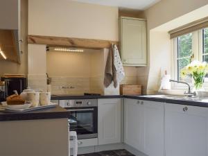 a kitchen with white cabinets and a sink at Wells Cottage in Hook Norton