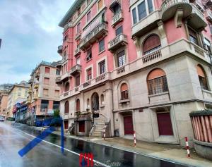 a tall pink building on a street with water in front at Porto Di Colombo - Affittacamere vicino spiaggia e città in Genoa