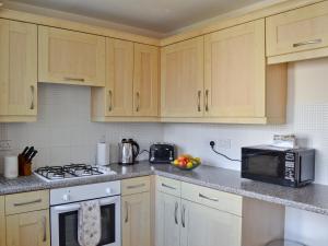 a kitchen with wooden cabinets and a stove and a microwave at The Marches in Anstruther