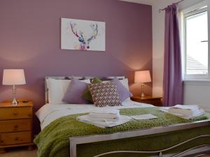 a bedroom with a bed with a green blanket at The Marches in Anstruther