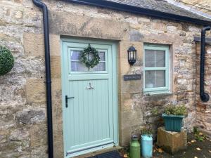 a stone cottage with a green door and windows at Mark Close Milking Parlour in Alston +3 photos