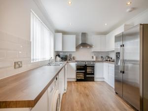 a kitchen with white cabinets and a stainless steel refrigerator at The Willows in Sea Palling