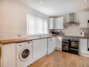 a kitchen with white cabinets and a washer and dryer at The Willows in Sea Palling