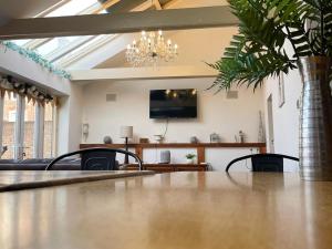 a living room with a table and a chandelier at Hobland Barn in Paston