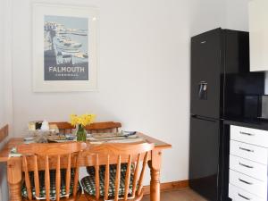 a kitchen with a wooden table and a black refrigerator at Linhay - Ukc4242 in Lanreath