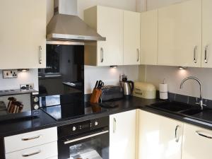 a kitchen with white cabinets and black counter tops at Linhay - Ukc4242 in Lanreath